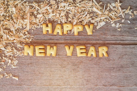 Happy new year text with bread and saw dust on wooden background