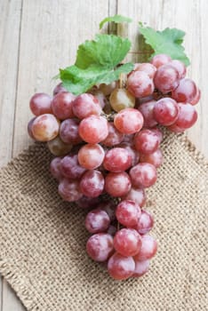 Red grape on natural sackcloth, closeup, on white background
