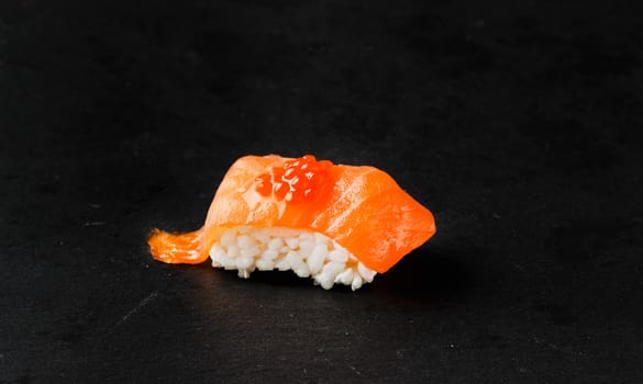 Salmon Nigiri with salmon roe on black slate stone.Raw fish in traditional Japanese sushi style. Horizontal image.