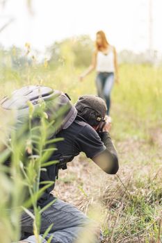 Man photographing young beautiful woman against in green field attractions, Summer time, outdoors, portrait of young couple in outdoors