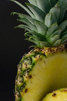 sliced pineapple fruit closeup on black background