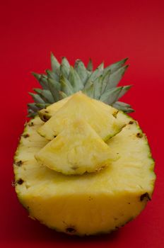 sliced pineapple fruit on red background, half of fruit with triangles
