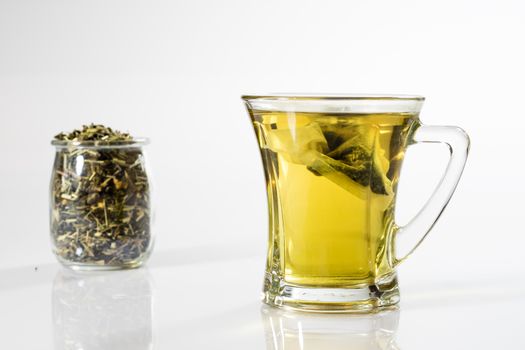 Tea in a glass on a white background. Green or fruit tea. Glass of white glass