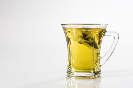 Tea in a glass on a white background. Green or fruit tea. Glass of white glass