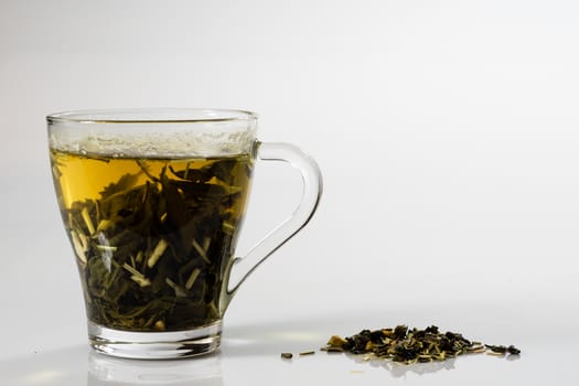 Tea in a glass on a white background. Green or fruit tea. Glass of white glass