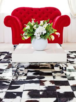 Red classical armchair in living interior with flowers on coffee table