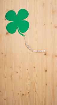 The words Happy Birthday and a cloverleaf on a cord on wood