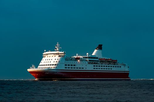 Red cruise liner. Passenger ship sailing from the sea in the morning
