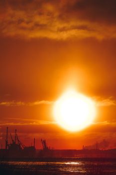 Hot orange winter sunrise against the cargo port