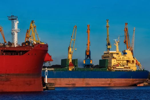 Red and blue cargo ship loading in the port of Riga
