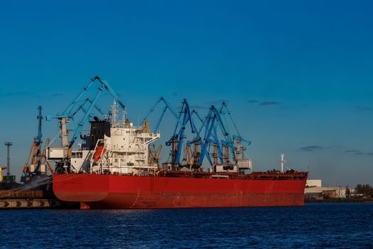 Red cargo ship loading in the port of Riga, Europe