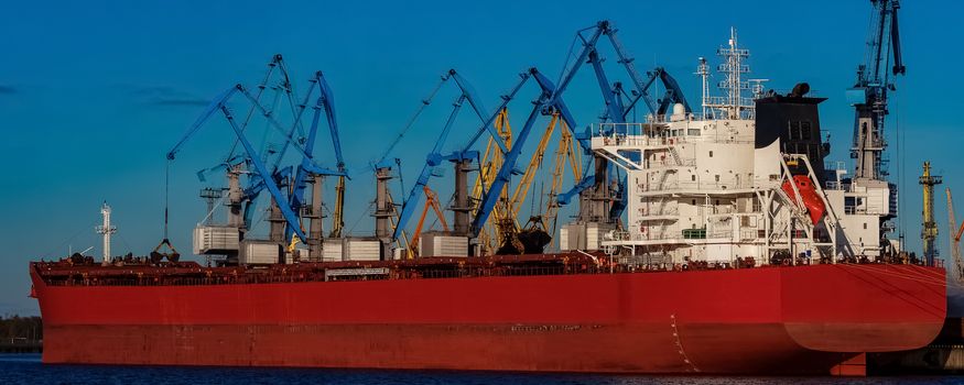 Red cargo ship loading in the port of Riga, Europe