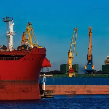 Red and blue cargo ship loading in the port of Riga