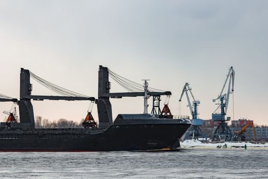 Black bulk carrier sailing to the sea in cold winter