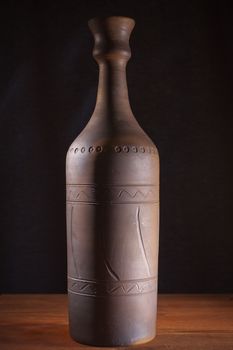 Clay bottle with wine on a wooden table