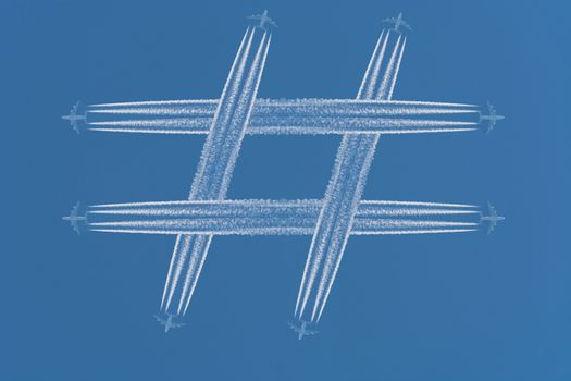 Four airplanes leave contrails in the form of the special sign # Hashtag against a dark blue sky.