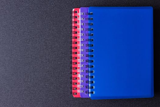 Several multi-colored notebooks on a spiral on a black background