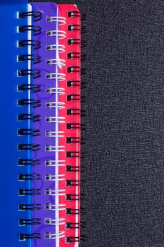 Several multi-colored notebooks on a spiral on a black background