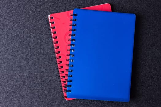 Several multi-colored notebooks on a spiral on a black background