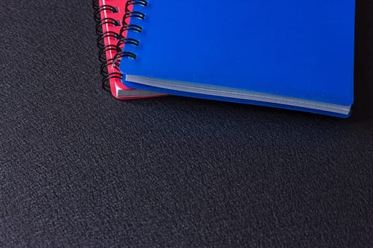 Several multi-colored notebooks on a spiral on a black background