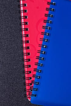 Several multi-colored notebooks on a spiral on a black background