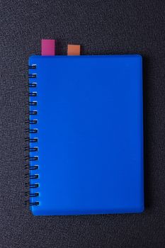 Blue notepad on a spiral with a sticker on a black background