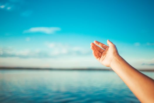 female hand on a background of lake and sky