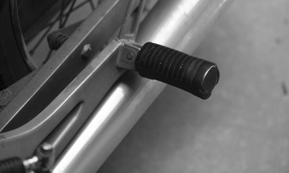 BLACK AND WHITE PHOTO OF CLOSE-UP OF MOTORCYCLE FOOT PEG