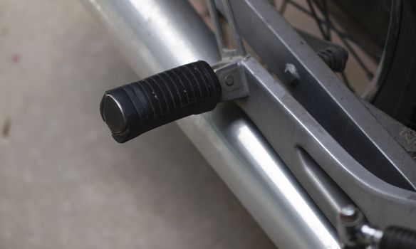 COLOR PHOTO OF CLOSE-UP OF MOTORCYCLE FOOT PEG