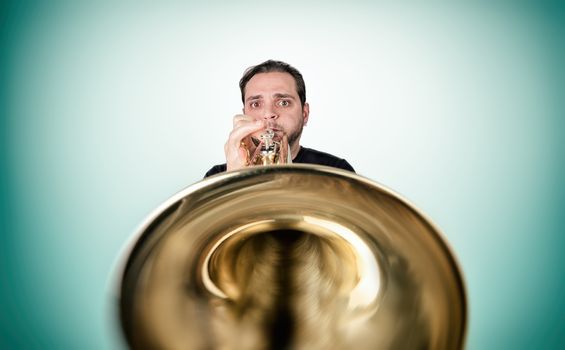 Funny man is playing trumpet looking in camera