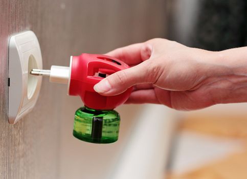 A woman puts a raptor from an insect into an electrical outlet.