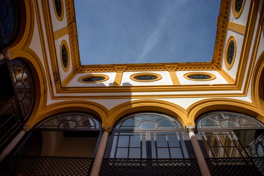 Yellow arch of a balcony against a blue sky in Seville, Spain, Europe