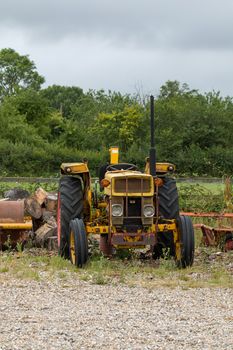 Old yellow tractor on waste ground.