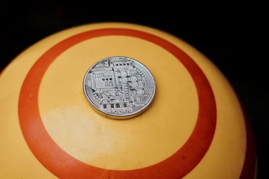 Digital currency physical silver bitcoin coin on yellow circle background.