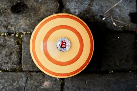 Digital currency physical silver red bitcoin coin on yellow background.