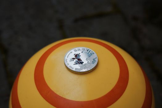Europe leaving. Silver brexit coin with british map on yellow circle background.