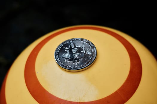 Digital currency physical silver bitcoin coin on yellow circle background.