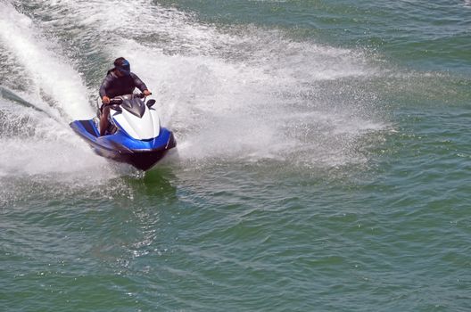 Aa speeding jet skier leaving a wake trail on Biscayne Bay off of Miami. Beach,Florida