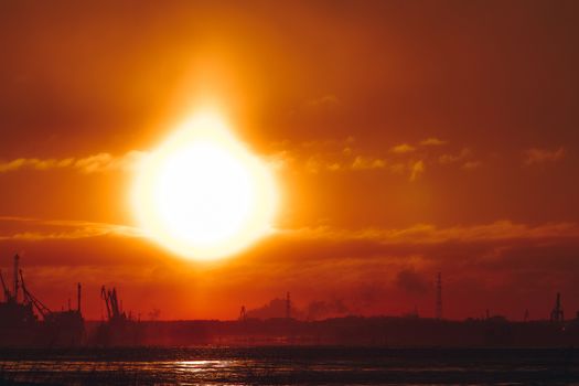 Hot orange winter sunrise against the cargo port