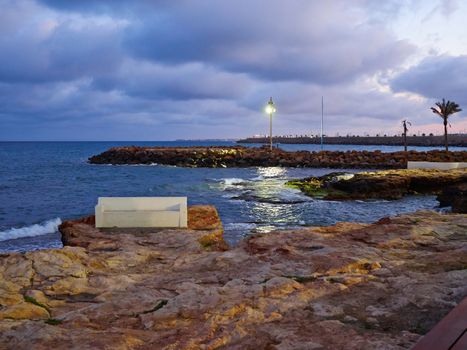 Bench made of stone in beautiful popular summer tourism destination Torrevieja beach, Costa Blanca, Valencia, Spain