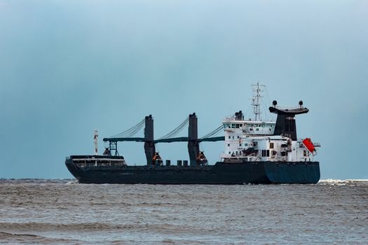 Black bulk carrier sailing to the sea in cold winter