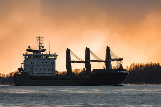 Black bulk carrier sailing to the sea in cold winter