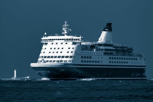 Passenger ship sailing from the sea in the morning. Toned dark blue