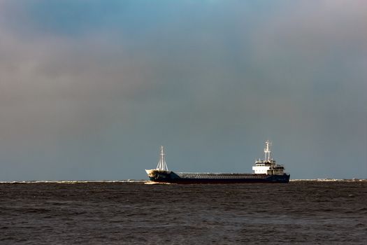 Blue bulk carrier moving from the sea in cold winter