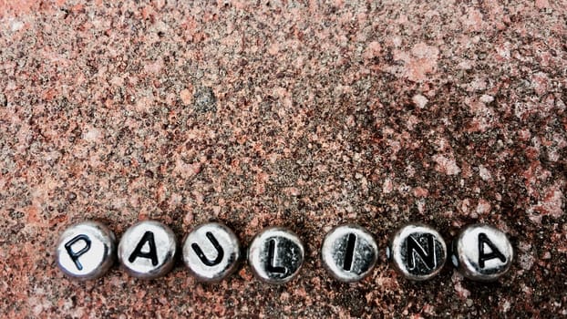 Small silver separate letters paulina inscription on dirty and old background.