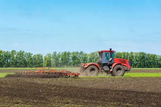 Tractor on the field plows the land, Russia, village, summer