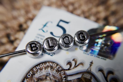 Small silver letters on metal stick. Blog on the five pound paper. Blog money concept.