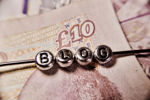 Small blog silver letters on ten pounds money background.