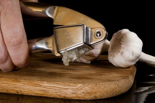 Garlic press and cloves of garlic laid on a wooden table background