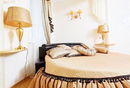 Cozy soft beautiful round bed in classical golden bedroom close up